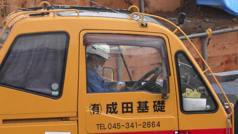 Side-View-Of-Operator-Sitting-In-The-Cabin-Of-A-Mobile-Crane-At-The-Construction-Site-On-A-Rainy-Working-Day