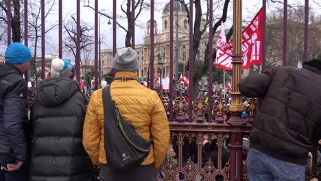 Gente-Detrás-De-La-Valla-Mirando-A-Los-Manifestantes-Contra-Las-Medidas-De-La-Corona-En-Viena