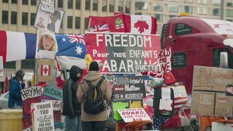 Two-Men-Talking-In-Front-Of-Placards-Blocking-The-Street-During-Freedom-Convoy-In-Ottawa,-Canada