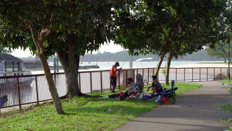 Familia-Pescando-Y-Haciendo-Un-Picnic-En-El-Parque-De-La-Playa-De-Changi,-Singapur