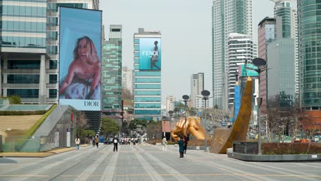 People-On-Facemasks-Walking-On-Gangnam-Streets-While-Advertisements-From-Dior-And-Fendi-Is-Playing-On-The-Background-At-Seoul-COEX--Static