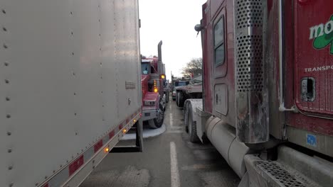 Freedom-convoy-protest,-Walking-Between-rows-of-trucks-on-street-blockage,-Tracking-shot