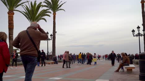 Multitud-De-Personas-Caminando-Por-Un-Típico-Paseo-Europeo-Con-Palmeras