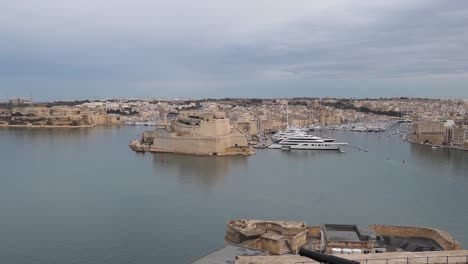 Panorámica-Con-El-Paisaje-Urbano-De-La-Ciudad-De-La-Valeta,-El-Puerto-Y-Los-Yates-De-Lujo-En-Malta-Desde-Upper-Barrakka-Gardens-Fort