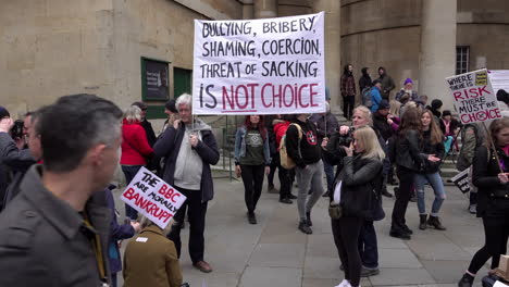 Two-people-hold-a-white-banner-that-reads-in-black-and-red-writing,-“Bullying,-bribery,-shaming,-coercion,-threat-of-sacking-is-not-a-choice”-on-a-protest-opposing-mandatory-Covid-vaccinations