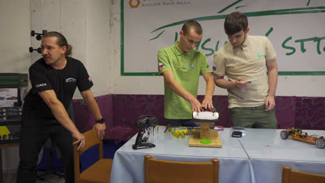 Adult-teacher-helping-young-male-students-build-electronic-remote-control-car-at-vocational-high-school-in-Slovakia
