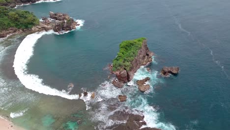 Drone-shot-of-coral-rocks,-the-waves-crashing-rocks-in-the-tropical-ocean,-Aerial-Jungwok-Beach-in-Gunung-Kidul-Regency,-Yogyakarta,-Indonesia