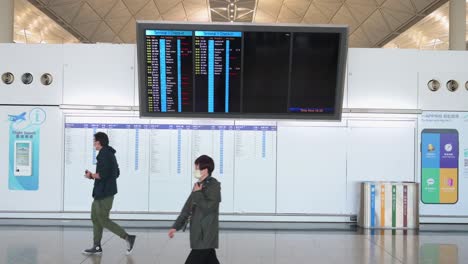 Ein-Passagier-Geht-An-Einem-Bildschirm-Vorbei,-Der-Anzeigt,-Wo-Die-Check-in-schalter-Der-Fluggesellschaften-Zugewiesen-Sind-Und-Sich-Auf-Dem-Internationalen-Flughafen-Chek-Lap-Kok-In-Hongkong-Befinden