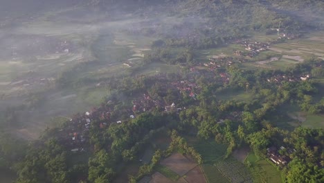 Luftbild-Von-Oben-Nach-Unten-Auf-Die-Landschaft-Mit-Plantage-Und-Kleinem-Dorf-In-Indonesien-Während-Eines-Sonnigen-Und-Nebligen-Morgens