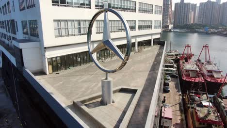 Mercedes-Benz-sign-spinning-on-top-of-Hong-Kong-Mercedes-Benz-main-showroom,-Aerial-view