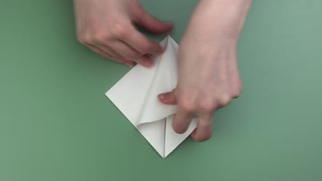 Hands-folding-origami-on-the-green-background-speeded-video
