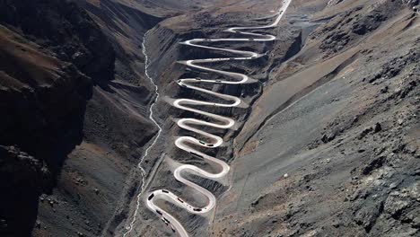 Aerial-dolly-tilt-down-view-of-the-cuesta-caracoles-road,-border-between-Chile-and-Argentina