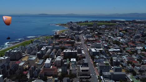 Toma-De-Drone-De-Sea-Point,-Ciudad-Del-Cabo---Drone-Está-Retrocediendo,-Viendo-Parapentes-Bajando-De-Signal-Hill