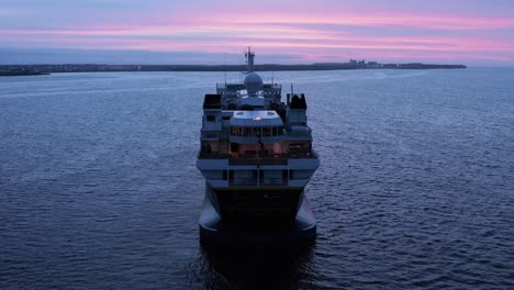 Stern-view-of-National-Geographic-Explorer-boat-in-calm-water-with-purple-sunset