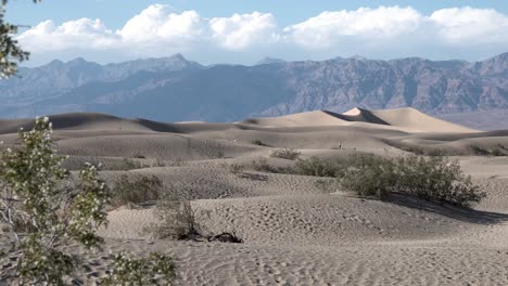 Distant-people-exploring-the-sand-dune-terrain-in-Death-Valley,-Mojave-Desert,-California,-Aerial-dolly-right-reveal-shot