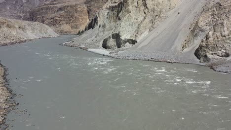 aerial-drone-panning-left-over-the-Indus-River-Valley-as-rapids-flow-fast-through-the-gorge-in-Skardu-Pakistan-surrounded-by-dirt,-mountains-and-rock-on-a-sunny-day