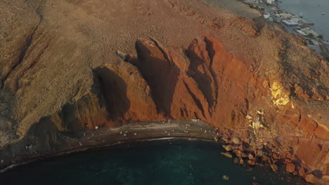 Aerial-tilt-view-of-eroded-red-cliffs-on-south-coast-of-Santorini