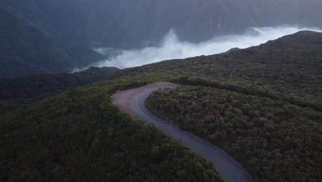 A-winding-road-with-low-clouds-at-sunset-in-Fanal,-Madeira