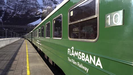 Flamsbanen-train-in-morning-sunlight---Moving-towards-Flamsbaba-logo-on-railway-car---Norway