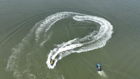 An-aerial-view-over-Gravesend-Bay-in-Brooklyn,-NY-as-two-jet-ski-riders-enjoys-the-beautiful-day-together