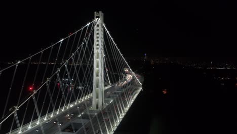 Luftaufnahme-Von-Fahrzeugen,-Die-Sich-Nachts-Auf-Der-San-Francisco-oakland-Bay-Bridge-Mit-Der-Stadt-Im-Hintergrund-Bewegen