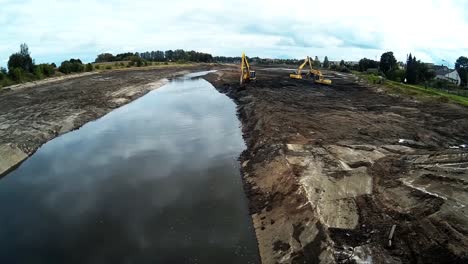 Tres-Excavadoras-Amarillas-Están-Trabajando-Con-Baldes-Para-Limpiar-Lodos-De-Lodo-Y-Escombros-Del-Fondo-Del-Río-Drenado