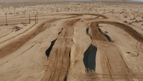 Flying-backwards-over-desert-motocross-circuit-as-rider-races-toward-camera