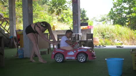 Mujer-Jugando-Con-Un-Niño-Pequeño-En-Un-Coche-De-Juguete-Rosa