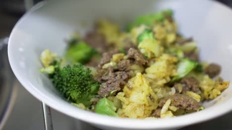 Putting-food-curry-rice-with-broccoli-and-beef-mince-meat-in-bowl-to-serve