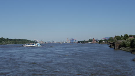 Ferry-crosses-freighter-on-Elbe-River-at-sunny-day-in-Hamburg,-Germany