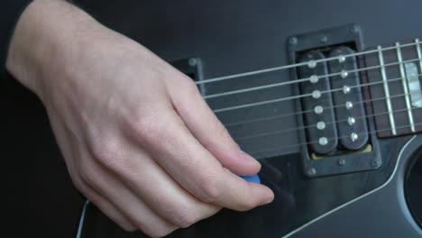 Man-Practising-a-vintage-black-electric-guitar,-rehearsing-chords,-solos-and-octaves-in-a-natural-light-environment.