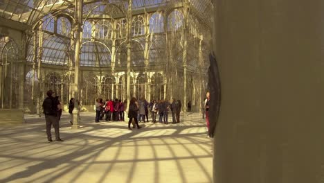 Tourists-inside-Palacio-de-Cristal-interior,-Retiro-park,-madrid,-slow-pan-wide