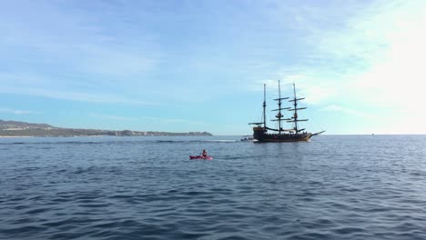 Menschen-Segeln-Im-Kajak-Auf-Dem-Meer-Vor-Einem-Piratenschiff-An-Einem-Sonnigen-Tag-In-Cabo-San-Lucas,-Mexiko