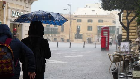 Personas-Que-Experimentan-La-Lluvia-De-Verano-En-La-Valeta,-Malta,-Alrededor-De-Marzo-De-2019.