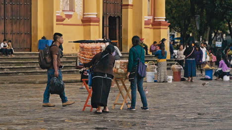 SELLING-FOOD-OUTSIDE-MAIN-CATHEDRAL-IN-SAN-CRISTOBAL-DE-LAS-CASAS,-CHIAPAS-MEXICO-SHOT-PEOPLE-PASSING-BY
