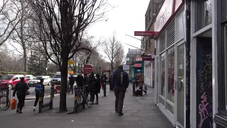 Uk-Febrero-2019---Gente-Caminando-Y-Montando-En-Bicicleta-Por-Las-Tiendas-En-Un-Pavimento-De-La-Calle-Alta-Arbolada