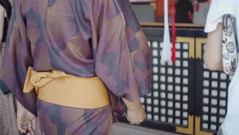 Guy-in-yukata-praying-and-shaking-the-bell-at-a-temple-in-Kyoto,-Japan-soft-lighting-slow-motion-4K