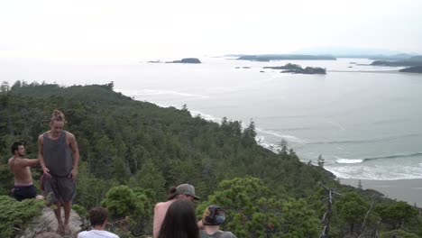 Young-men-and-women-hiking-and-exploring-the-coastline-hills-of-Vancouver-Island,-British-Columbia,-Canada,-Pan-right-reveal-shot