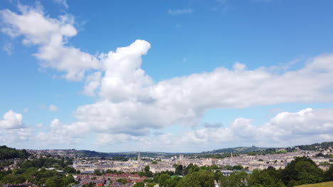 Aufnahme-Der-Skyline-Der-Stadt-Bath-Vom-Aussichtspunkt-Am-Hang-An-Einem-Sonnigen-Sommertag,-Der-In-Den-Blauen-Himmel-Mit-Weißen,-Flauschigen-Wolken-übergeht