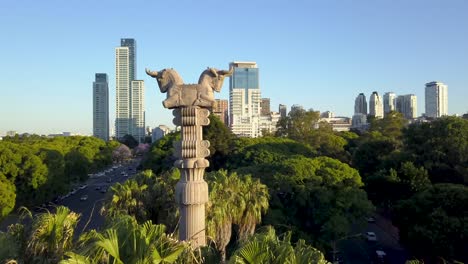 Toma-Aérea-De-Paralaje-De-Una-Columna-Persa-En-Los-Bosques-De-Palermo-Y-La-Ciudad-De-Buenos-Aires