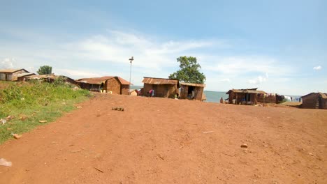 Un-Punto-De-Vista-Bajo-Desde-Una-Moto-Que-Viaja-Por-Un-Camino-De-Tierra-Y-Pasa-Por-Un-Pueblo-Rural-Africano