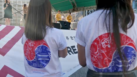 Zwei-Weibliche-Koreanische-Freiwillige-Klatschen-Während-Des-Koreanischen-Festivals-Vor-Der-Bühne