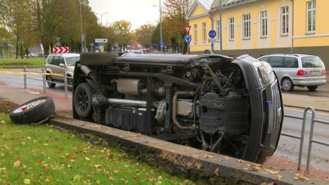 The-car-crashed-in-the-city-center,-lying-on-one-side-on-a-pedestrian-sidewalk