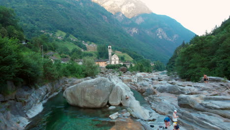 Antena-Que-Revela-Dolly-Hacia-Una-Iglesia-Sobre-El-Río-Verzasca,-Suiza