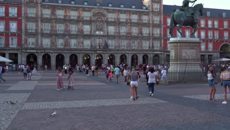 Inclinación-Lenta-Hacia-Abajo-Desde-El-Cielo-Hasta-La-Plaza-Mayor-Con-Gente-Caminando-A-Través-Del-Marco