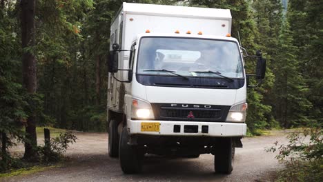 Statische-Aufnahme-Eines-Mitsubishi-Fuso,-Der-Auf-Einer-Unbefestigten-Straße-In-Einem-Wald-In-Yukon,-Alaska,-Um-Eine-Ecke-Biegt