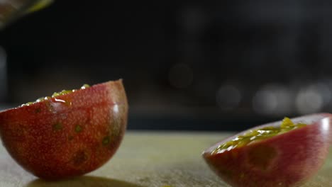 Close-up-shot-of-person-cutting-a-passion-fruit-in-two-pieces-on-wooden-table