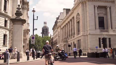 Ciclistas-Cruzando-Great-George-Street-En-Londres,-Transporte-Público-Saludable,-Reconstrucción-Del-Big-Ben-En-El-Fondo,-Día-Soleado