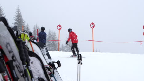 Esquiadores-Esquiando-Durante-Nevadas,-Esquís-Y-Snowboard-En-Primer-Plano