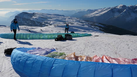 Paragliding-pilots-prepping-the-colorful-canopies-to-fly-tourists-off-the-top-of-a-mountain-in-Trentino,-Italy
